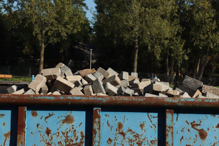 Loaded dumpster or disposal bin near a construction site, loaded with bricks
