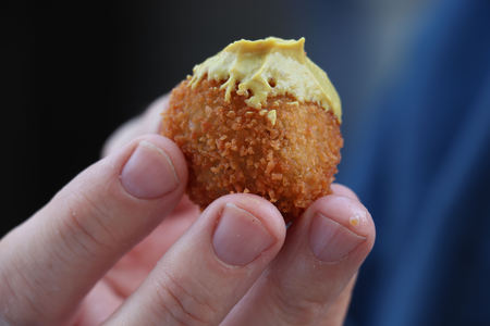 Dutch snack:  Man eating a bitterbal with mustard. Warm stuffed fried meatballs, often served with alcoholic drinks as "bittergarnituur", a Dutch name for snacksの写真素材