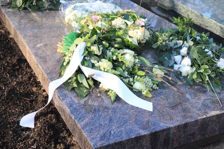 Sympathy flowers with satin ribbons on a grave