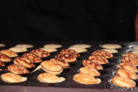 Poffertjes, Dutch small, fluffy pancakes, made on hot cast iron plate, served with powdered sugar and butter.の写真素材