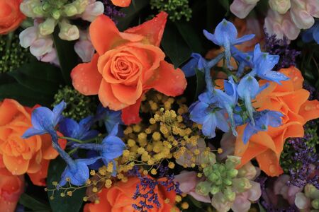 Orange and blue flower arrangement for a wedding: orange roses and blue larkspur 