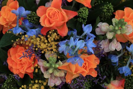 Orange and blue flower arrangement for a wedding: orange roses and blue larkspurの写真素材