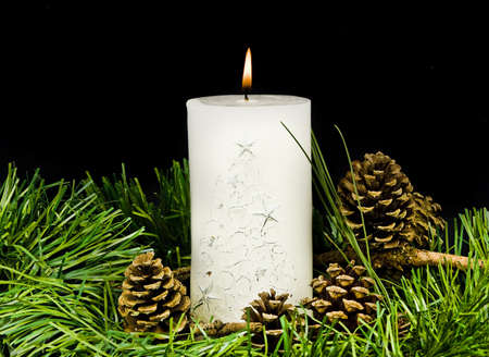 Pine cone and christmas greens and burning candle の写真素材