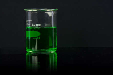 lab glass with green chemical on black の写真素材