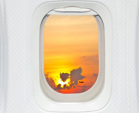 Aircraft window with view of sunrise and planeの写真素材
