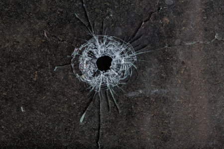 Bullet hole in glass on dirty grungy black background