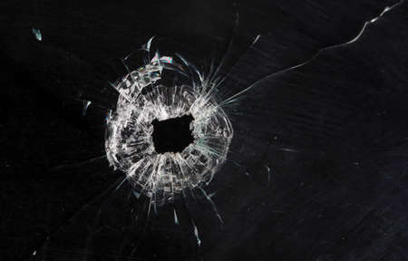bullet holes in glass isolated on blackの写真素材