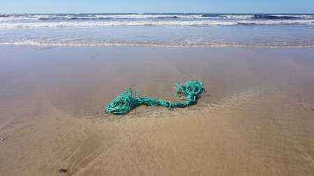 Aerial view of a green plastic trash on the beach.