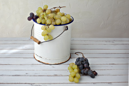 grapes in an old metal bucket over a wood tableの写真素材