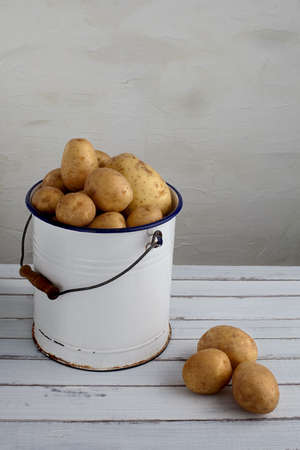 potatoes in an old iron bucket on a wood tableの写真素材