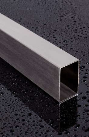 stainless steel square pipe, on a black surface with water dropsの写真素材