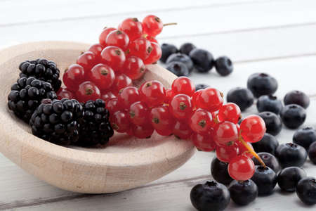 brambleberries, currants and blueberries on a white rustic tableの写真素材