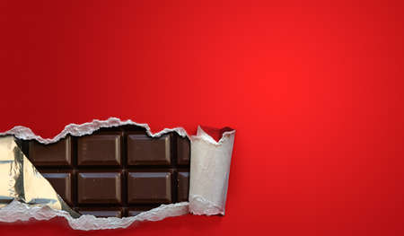 Dark chocolate bars in a red package strip open. Background with copy space.
