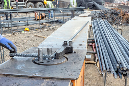 Construction worker is bending to rebars with tool. Rebar, also known as reinforcement steel and...