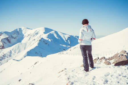 Woman hiker, healthy lifestyle. Trekking and hiking on snow white winter nature, beautiful inspirational mountain landscape.の写真素材