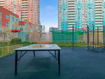 Tennis table on the playground in the courtyard of a residential building. Reflection in water and a puddle. Mobilephoto. Copy spaceの写真素材