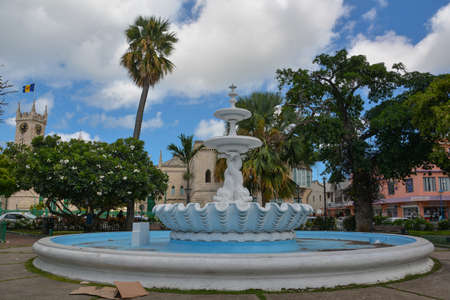 Bridgetown, Barbados, Caribbean - 22 Sept 2018: Fountain in front of parliament with flag and clock on the tower. White clouds in the blue skyのeditorial素材
