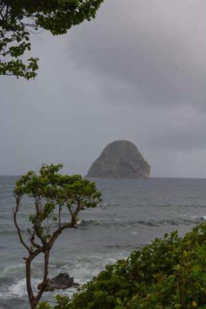 Landscape seascape view of the famous Diamond rock (rocher du Diamant) in the lumpy sea with grey sky and clouds, Martinique, Antilles, West Indiesの写真素材