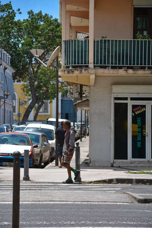Point-a-Pitre, Guadeloupe - Sept 17, 2018: Homeless man in dirty clothes with a gray-haired head walks down the street in a sweater, shorts, sneakersのeditorial素材