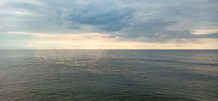 sea horizon. A lone ship drifts over the horizon under the soft rays of the summer sun breaking through low cloudsの写真素材