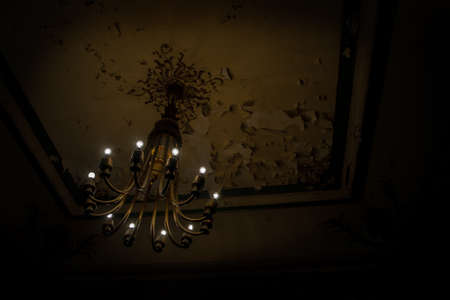 Interior scene of a chandelier in a grungy and dark concrete wasted room.の写真素材