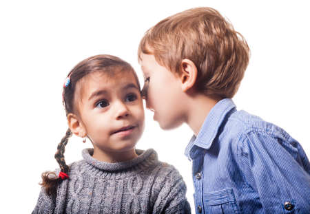 Boy whispering to a girl on white background の写真素材