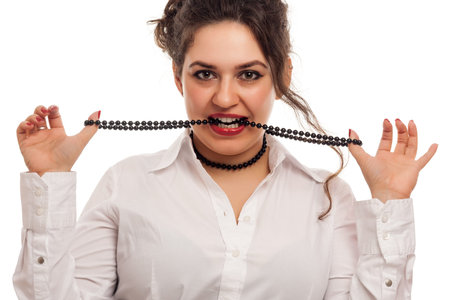 confident woman playing with necklace on white の写真素材