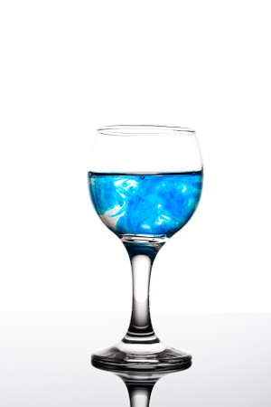 Classy backlit glass of water with blue coloring disolwingの写真素材