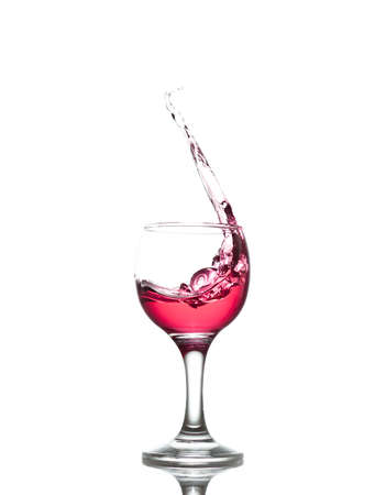 red drink splashes out of glass on white backgroundの写真素材