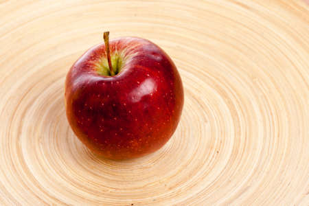 big red apple in middle of a wooden plateの写真素材