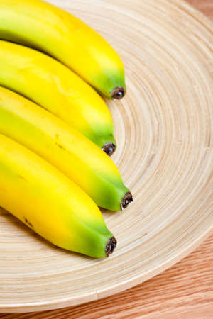 fresh yellow banana on brown wooden plateの写真素材
