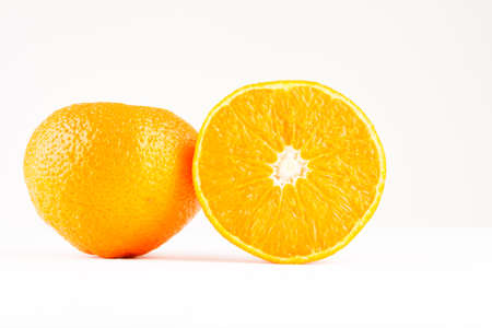 two mandarines one whole one sliced on white backgroundの写真素材