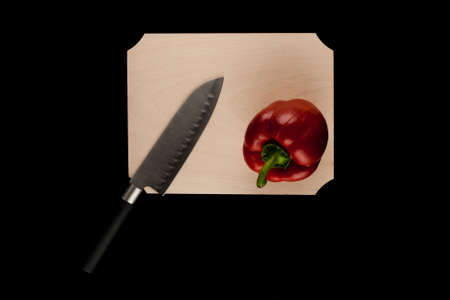 pepper with knife on wooden cutting board on black backgroundの写真素材