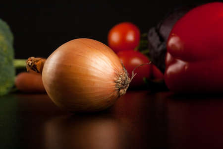 onion on black with different vegetables in the backgroundの写真素材