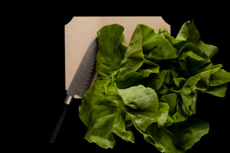 salad with knife on wooden cutting board on black backgroundの写真素材