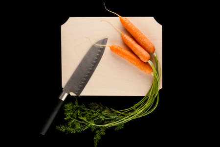 carrots with knife on wooden cutting board on black backgroundの写真素材