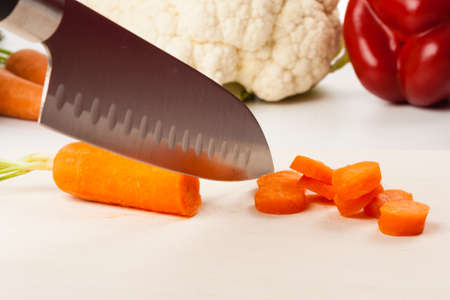 Carrot on cutting board with different vegetables in the backgroundの写真素材