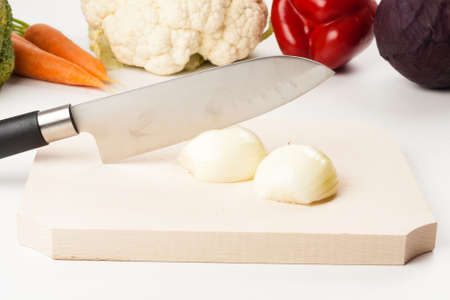 onion on cutting board with different vegetables in the backgroundの写真素材