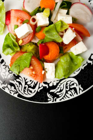 vegetable salad in stylish balck and white plate on black backgroundの写真素材
