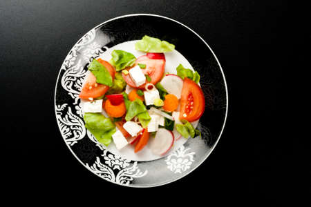 vegetable salad in stylish balck and white plate on black backgroundの写真素材