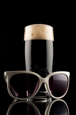 glass of black beer with white sunglassの写真素材