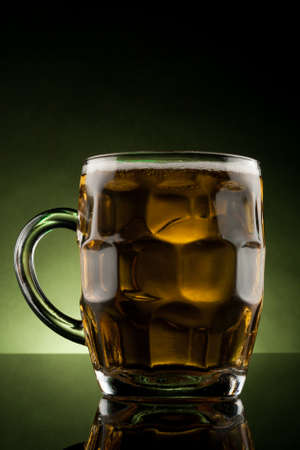 back lit glass mug with beer with reflectionの写真素材