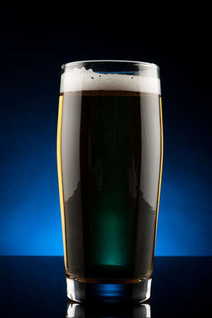 back lit glass of beer with reflectionの写真素材