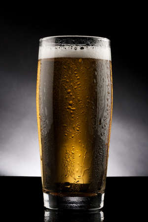 back lit glass of beer with water dropsの写真素材
