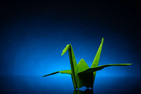 green origami paper crane with blue back lightの写真素材