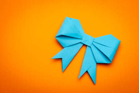 blue origami paper bow on orange paper backgroundの写真素材