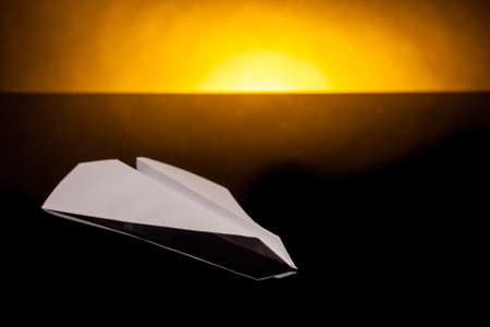 white papaer plane with orage back lightの写真素材