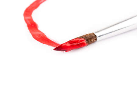 paint brush with red paint on white paperの写真素材