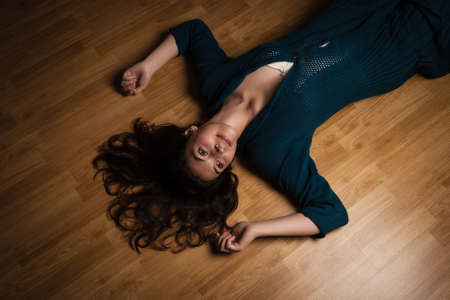 elegant female in dark room relaxing on the floorの写真素材