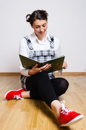 young woman sitting on the floor and reading a book